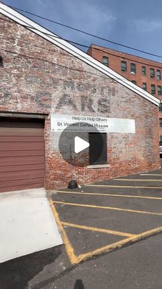 an empty parking lot in front of a brick building with graffiti on the wall and garage doors