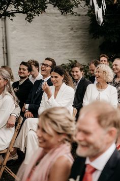 a group of people sitting next to each other at a wedding ceremony in front of an audience