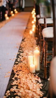 candles are lined up on the aisle at an outdoor wedding