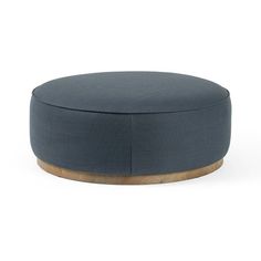 a blue round ottoman with wooden legs and an upholstered cushion on the top