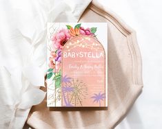 a baby shower book on top of a bed next to white flowers and feathers in the background