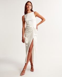 a woman is wearing a white dress with a slit down the side and her hand on her hip