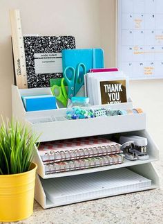 an office desk with various stationery items on it and a plant in the corner