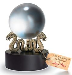 a metal ball and two silver dragon figurines on a black base with a tag