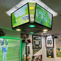 the inside of a sports shop with two televisions on the ceiling and football memorabilia hanging from the ceiling