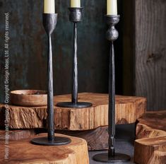 three candles sitting on top of wooden logs