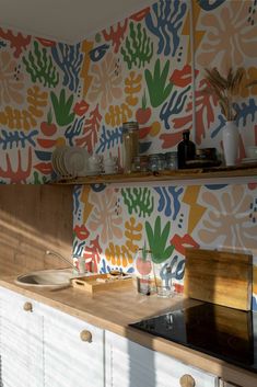 a kitchen with colorful wallpaper and wooden cabinets