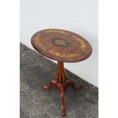 a small wooden table sitting on top of a cement floor next to a white wall