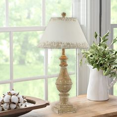 a lamp sitting on top of a wooden table next to a vase filled with flowers