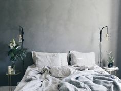 an unmade bed with white linens and flowers on the nightstand next to it