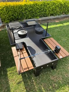 an outdoor table with grills on it in the grass