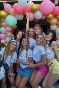 a group of young women standing next to each other in front of a balloon arch