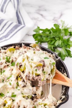 a skillet filled with meat and vegetables covered in gravy, garnished with parsley