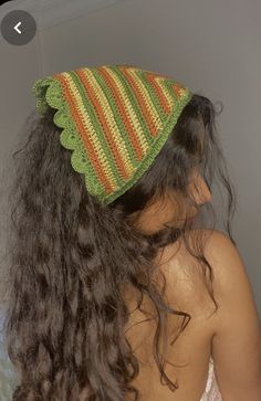 a woman with long brown hair wearing a green and orange knitted hat on her head