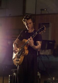 a man playing an electric guitar in front of a microphone and some other musical equipment