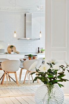 a vase with flowers sitting on top of a table next to chairs and a stove