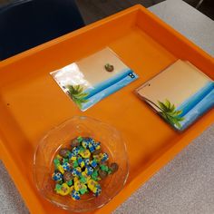 an orange tray with two cards and a bowl of dices on it, along with other items