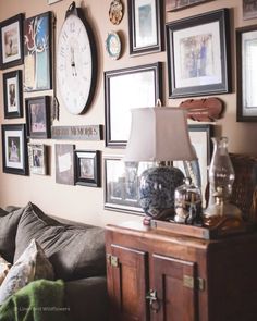 a living room filled with lots of pictures on the wall and a clock above it