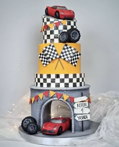 a three tiered cake decorated with cars and checkered flags on the top layer