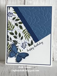 a blue and white birthday card with a butterfly on the front, sitting on a wooden surface