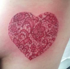 a red heart shaped tattoo on the back of a woman's shoulder and arm