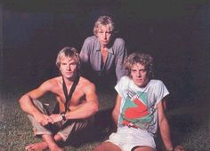 three men sitting on the ground posing for a photo