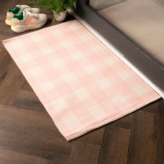 a pink and white checkered rug sitting on top of a wooden floor next to a pair of shoes