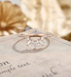 a diamond ring sitting on top of a piece of paper next to a gold flower