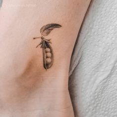 a woman's foot with a tattoo on it that has a pea pod attached to it