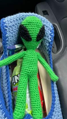 an alien stuffed animal sitting in the middle of a car seat