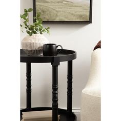 a black table with a white vase sitting on top of it next to a chair