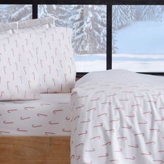 a bed with white and red sheets in front of a window overlooking the snow covered mountains