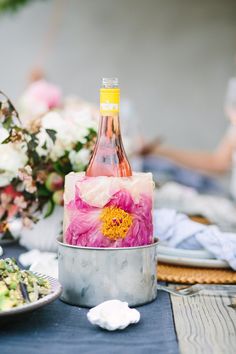 a bottle of wine sitting on top of a table next to other plates and flowers