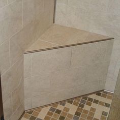 the corner of a shower stall with tile flooring and wall tiles on the walls