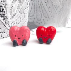 two red and black hearts sitting next to each other on a white tablecloth covered surface