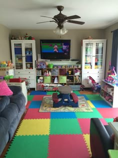 a child's playroom with toys, bookshelves, and couches