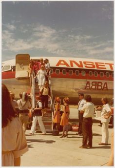 people getting off an airplane on the tarmac at an airport with stairs leading up to it