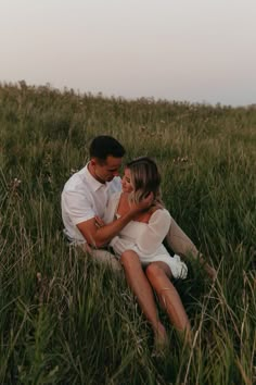 a man and woman sitting in tall grass