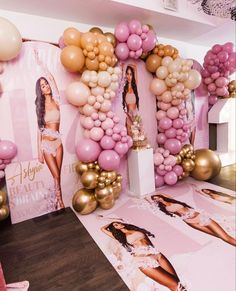 a table topped with balloons and pictures next to a wall covered in pink and gold