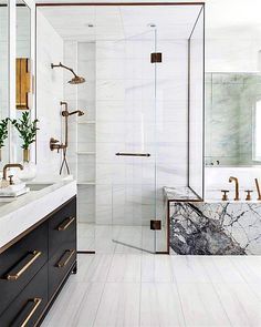 a white bathroom with marble counter tops and gold accents on the shower door, tub, and sink