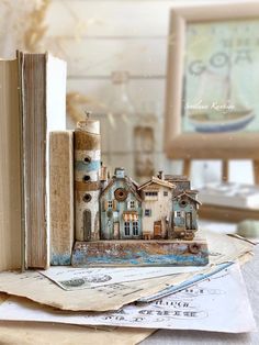 an old book is sitting on top of a table next to a small model house