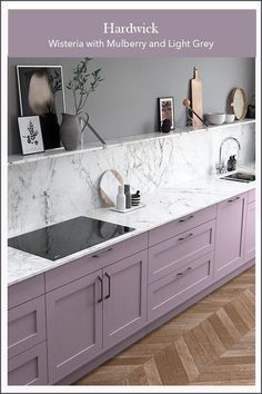 a kitchen with purple cabinets and marble counter tops, along with pictures on the wall