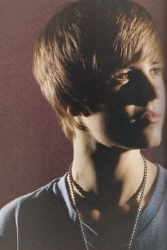 a young man wearing a necklace and looking off into the distance