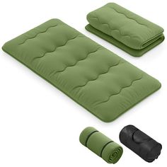 two green and one black sleeping bags with rolled up blankets on them next to each other