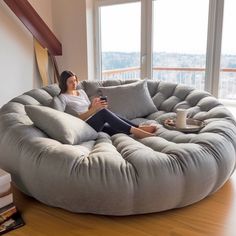 a woman is sitting on a bean bag chair in the living room with a cup of coffee