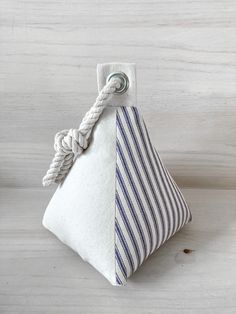 a white and blue striped bag with a knot on the handle sitting on a wooden surface