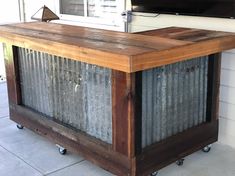 an outdoor bar made out of corrugated tin and wood with wheels on the front porch