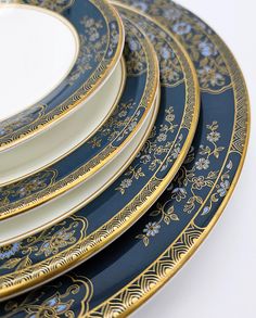 four blue and gold plates stacked on top of each other, with one plate in the middle