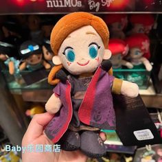 a person holding up a stuffed doll in front of a store shelf with other items