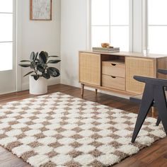 a white and brown rug in a living room next to a wooden table with a potted plant on it